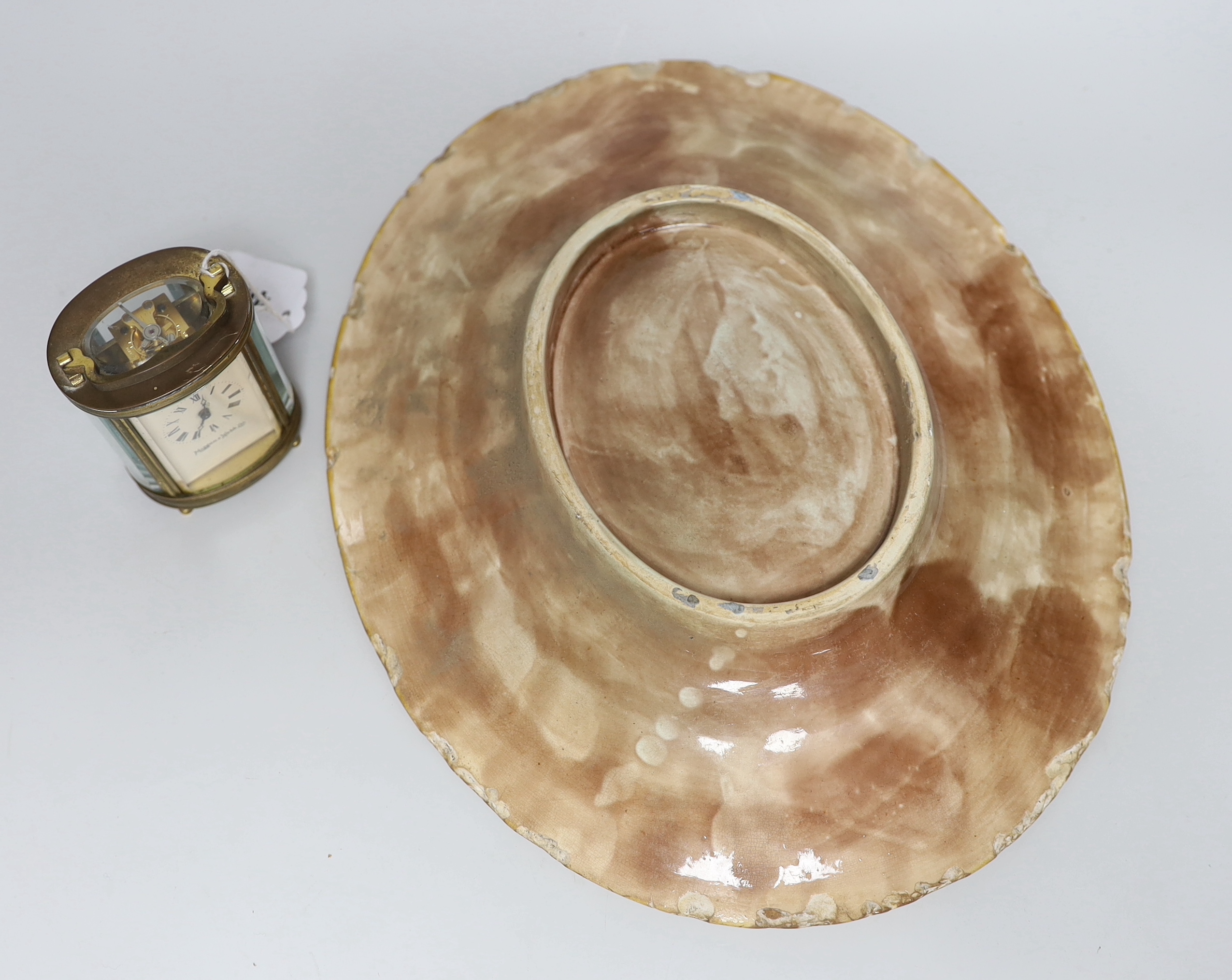 A small oval lacquered brass carriage timepiece retailed by Mappin and Webb together with an oval majolica dish. 32cm long